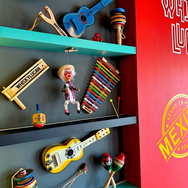 Shelves filled with colorful Mexican folk art, including guitars, maracas, and a puppet.
